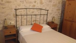 a bedroom with a bed with an orange pillow on it at Casa Solé in Villalba dels Arcs