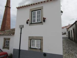 um edifício branco com duas janelas numa rua em Casa do Forno em Almeida
