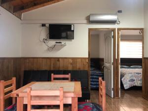a dining room with a table and a bedroom at Cabañas Llancahue in Valdivia