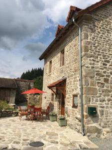 a stone building with a table and chairs and an umbrella at Maison de Bois Royale in Royère-de-Vassivière