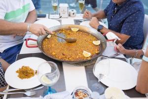 a group of people sitting around a table with a pan of food at Ocean Lounge in Altea