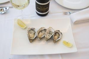 three oysters on a plate with a bottle of wine and a glass at Ocean Lounge in Altea