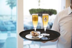 a man holding a tray with two champagne glasses at Ocean Lounge in Altea