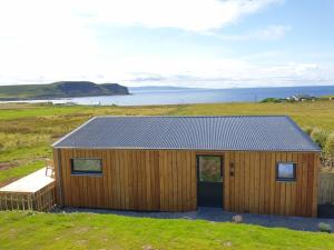 a wooden house with a solar roof in a field at Flora's Cliff View in Kilmuir