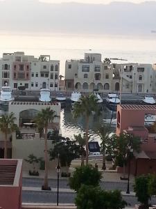 Sea View Apartment at Tala Bay Resort in Aqaba في العقبة: اطلاله على مدينه بها مباني والنخيل