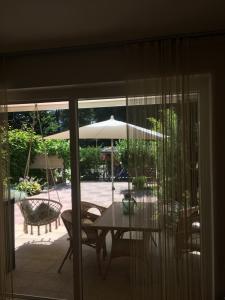 クルンペンドルフ・アム・ヴェルターゼーにあるSee Appartment Wörtherseeのテーブルと椅子と傘のあるパティオ