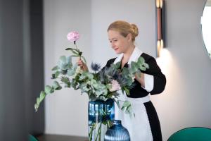 a woman is arranging a vase of flowers at Hotel Plaza e de Russie - Relais & Ch&acirc;teaux in Viareggio