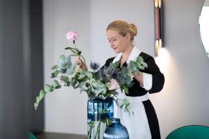 Una mujer está arreglando un jarrón de flores. en Hotel Plaza e de Russie - Relais & Châteaux, en Viareggio