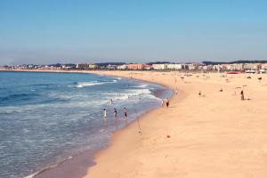 a group of people walking on a beach at Hotel Apartamento Solverde in Espinho