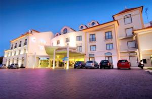 um grande edifício com carros estacionados em um estacionamento em LAM Hotel Estarreja em Estarreja