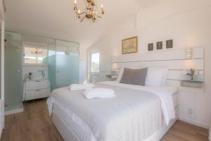 a white bedroom with a large white bed and a mirror at Casa Luisandra Boutique Hotel B&B in Luz