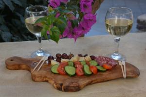 ein Holzschnitttafel mit Gemüse und zwei Gläsern Wein in der Unterkunft ThalaSEA - village Antiparos in Antiparos