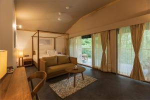 a living room with a bed and a couch and a table at WelcomHeritage Ayatana, Coorg in Somvārpet