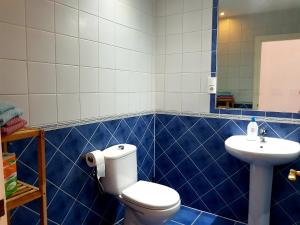 a blue tiled bathroom with a toilet and a sink at Lina Mogan in Puerto de Mog&aacute;n