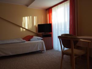 a bedroom with a bed and a chair and a television at Pensjonat Anker pokoje in Ustronie Morskie
