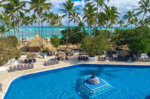 a beach with a pool, chairs, and a blue sky at Grand Sirenis Punta Cana Resort & Aquagames - All Inclusive in Punta Cana