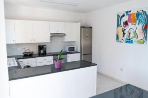 a kitchen with white cabinets and a stainless steel refrigerator at Helios Cottages in Paphos City