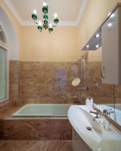 a bathroom with a sink and a tub and a chandelier at Villa Basileia Riverside in Karlovy Vary