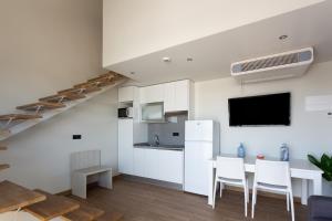 a kitchen with white cabinets and a table and chairs at Apartamentos Playa De Los Barcos in Isla