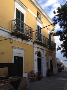 - un bâtiment jaune et blanc avec balcon dans l'établissement Hotel Mezzatorre, à Ventotene