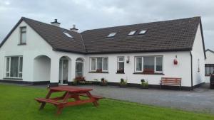 a white house with a picnic table in front of it at Puffin rooms in Lisdoonvarna