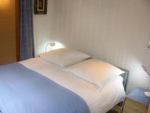 a bed with white sheets and pillows in a room at Appartement Beauchocty in Evolène
