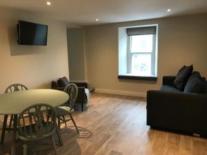 a living room with a table and a couch at Bush House Accommodation - The Courthouse Apartment in Bushmills