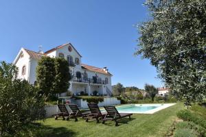 a villa with a swimming pool and chairs in the yard at Casa nas Serras in Vila Nova de Poiares