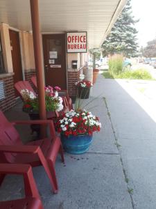 a gas station with red chairs and flowers on the sidewalk at Liberty Inn in Bowmanville