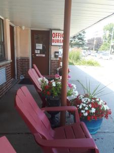 uma cadeira vermelha sentada à porta de um café com flores em Liberty Inn em Bowmanville