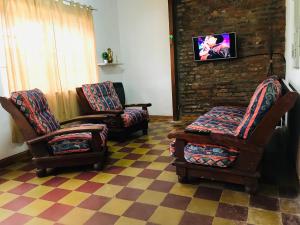 een woonkamer met 2 stoelen en een televisie bij House in San Antonio de Areco