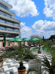 a resort with a pool with green umbrellas and a building at Allure Beach Resort Aparthotel in Primorsko