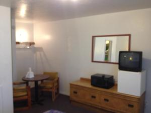 Budget Inn في غرين ريفر: غرفة معيشة مع تلفزيون على خزانة وطاولة