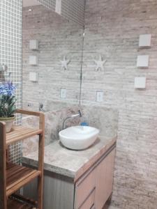 La salle de bains est pourvue d'un lavabo et d'un mur en pierre. dans l'établissement Apartamentos Hotel Marinas, à Tamandaré