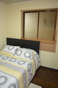 um quarto com uma cama e uma janela com uma colcha em #5 Private room close to Airport em Alajuela