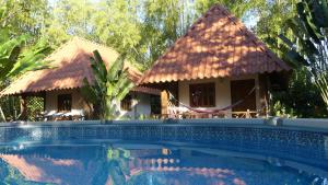 a resort with a swimming pool in front of a house at Naturalmente Boutique Bungalows y Cocina Mediterránea in Las Lajas