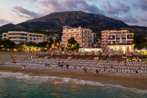 una spiaggia con un gruppo di sedie e edifici di Sunset Hotel a Dobra Voda