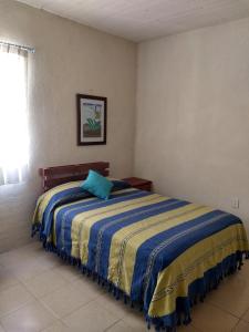 a bedroom with a bed with a blue pillow on it at Tu casa Oaxaca... in Oaxaca City