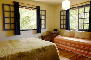 a bedroom with two beds and two windows at Sítio Flor das Águas in Lumiar