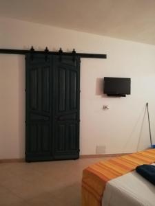 ein Schlafzimmer mit einer schwarzen Tür und einem TV an der Wand in der Unterkunft Al 101...sogni... in Villa San Pietro