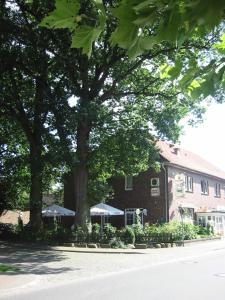 a building with trees and umbrellas in front of it at Landhotel Heiner Meyer in Wahrenholz