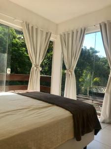 a bedroom with a large bed and large windows at Villa Bella Vista in Cabo Frio