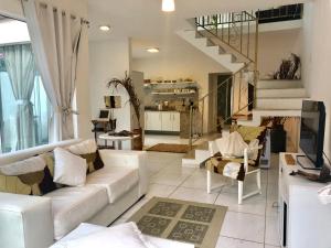 a living room with white furniture and a staircase at Villa Bella Vista in Cabo Frio