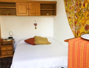 a small bedroom with a white bed and wooden cabinets at Casa de Amig@s en Santa Cruz de la Palma in Santa Cruz de la Palma