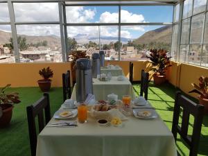 einen Tisch mit Essen in einem Zimmer mit Fenstern in der Unterkunft Colca Andina Inn in Chivay