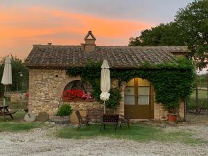 un edificio de piedra con sombrilla, mesa y sillas en Agriturismo Podere dell' Olmo, en Amelia