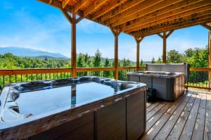 bañera de hidromasaje en una terraza con parrilla en Foxwood Mansion Cabin, en Pittman Center