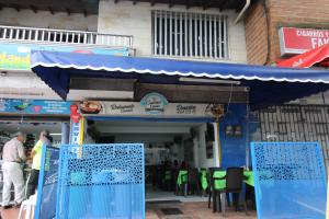 a restaurant with a blue awning and tables and chairs at HOTEL MANAGER OBELISK in Medellín