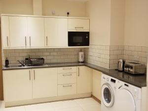 uma cozinha com armários brancos e uma máquina de lavar roupa em London Luxury Apartments 1min walk from Underground, with FREE PARKING FREE WIFI em Londres