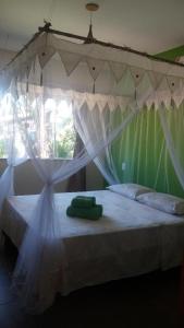 Una cama con dosel y dos toallas verdes. en PachaMama Flats - Taipu de Fora, en Barra Grande